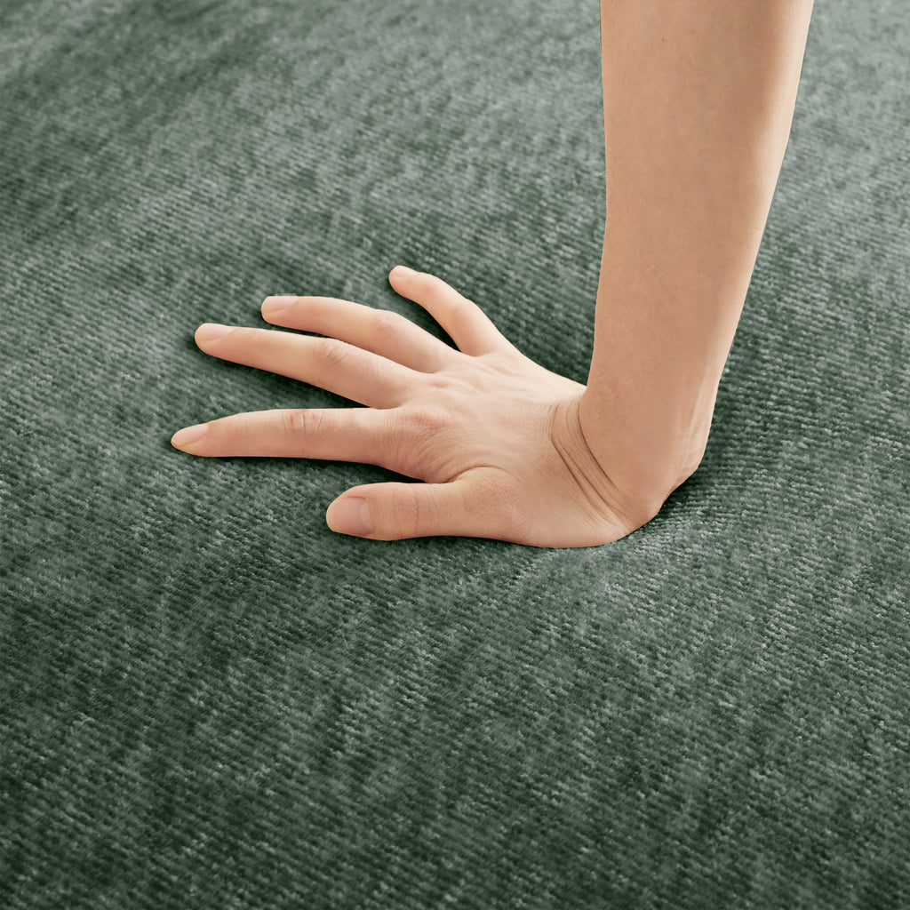 Hand pressing into the seat of the Velvet Modular U Shape Sofa, illustrating the deep cushioning and soft velvet surface.