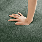 Hand pressing into the seat of the Velvet Modular U Shape Sofa, illustrating the deep cushioning and soft velvet surface.