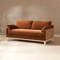 Modern farmhouse sofa in burnt orange performance velvet with two side cushions and light wood tapered legs.