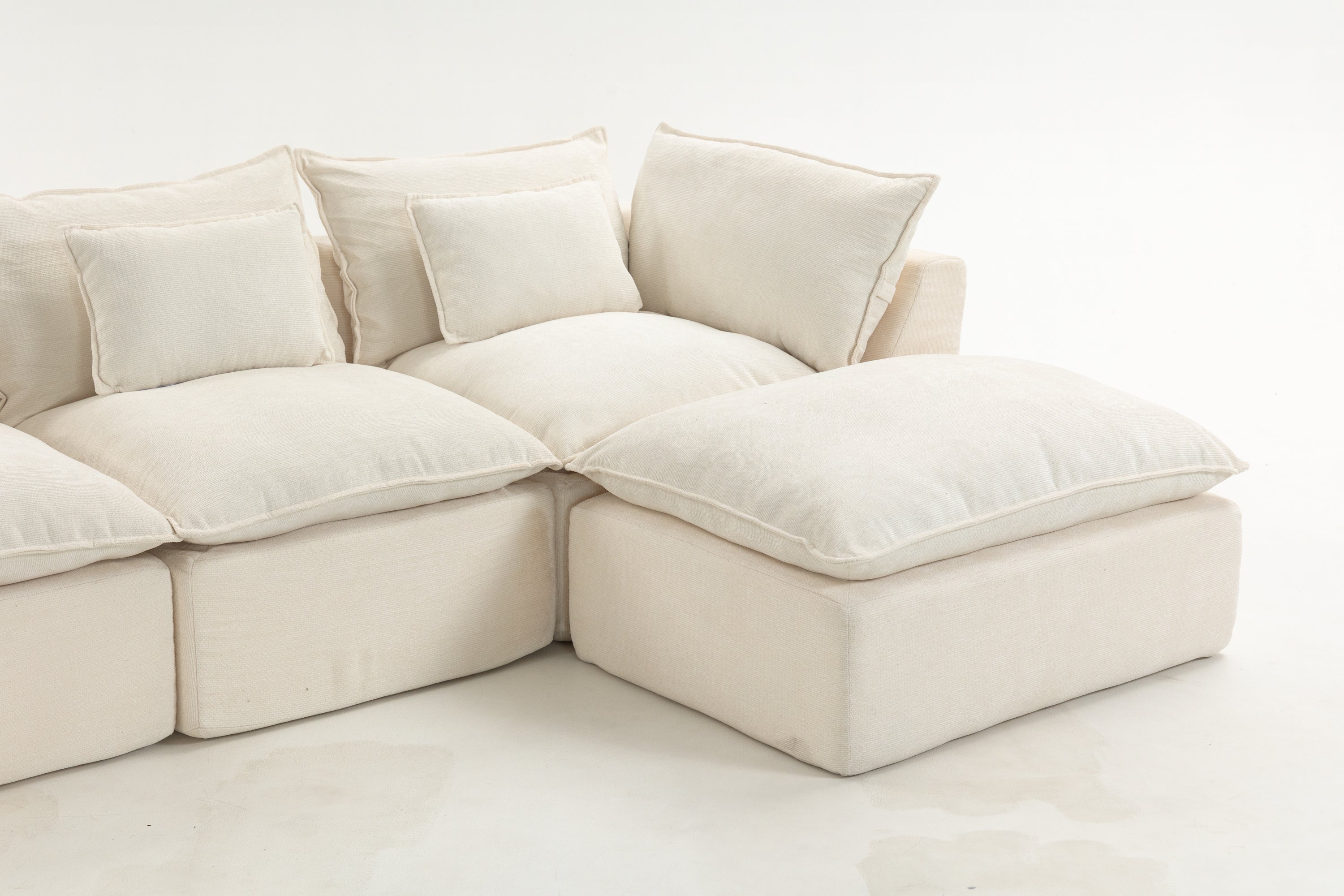 Right corner of oversized modular sectional sofa with deep seating and soft cushions. Cream fabric enhances cozy cloud couch appeal.