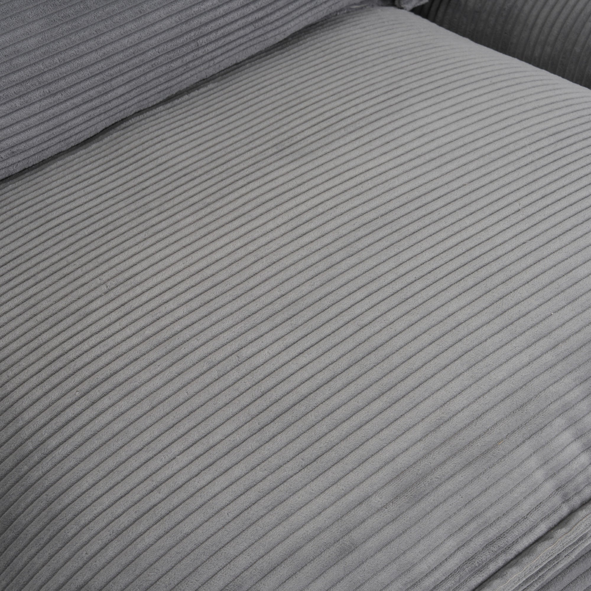 Detailed view of seat cushion surface on dark grey modular sofa, showcasing soft corduroy texture and plush upholstery.