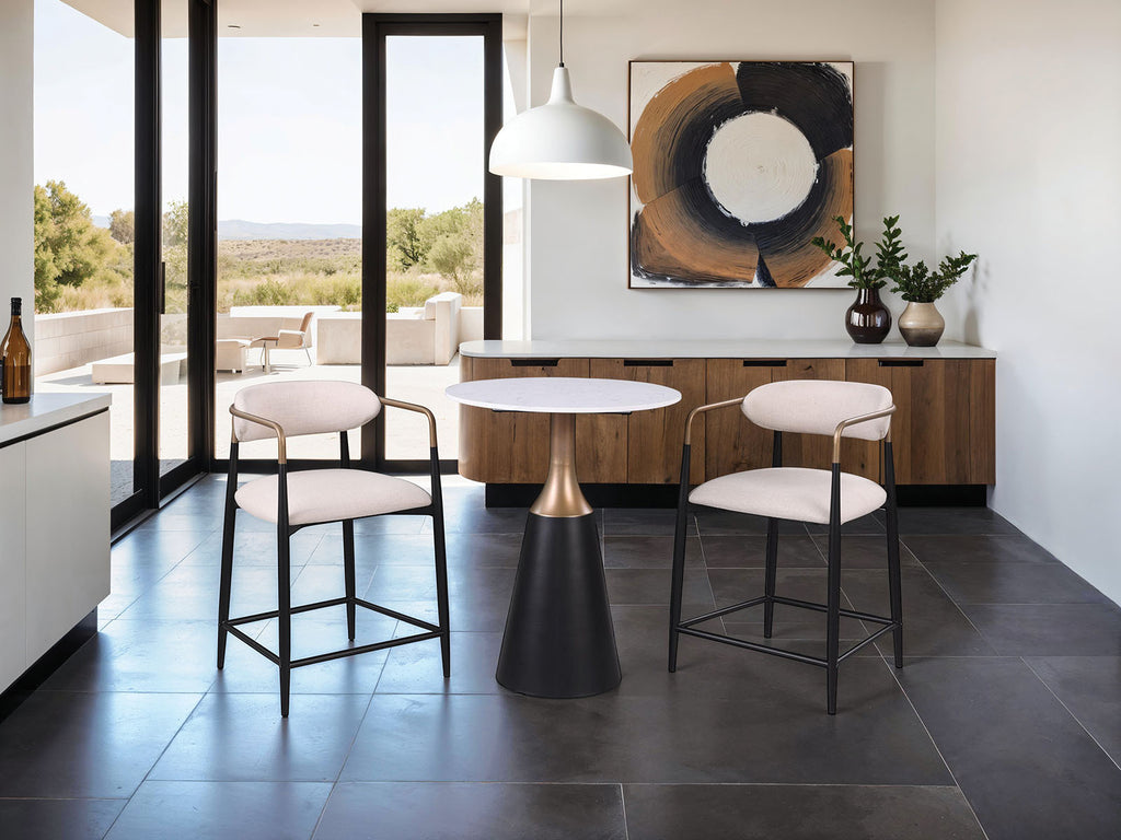 Modern kitchen setup with two contemporary counter height chairs featuring black metal legs, gold accents, and beige cushions.