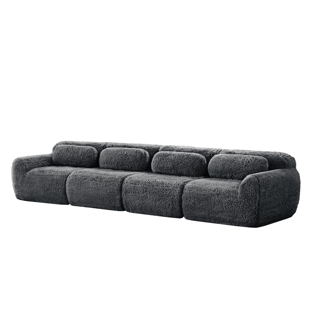 Angled side view of 149'' modular plush sofa in dark grey, showcasing its rounded edges and deep cushioned seats.