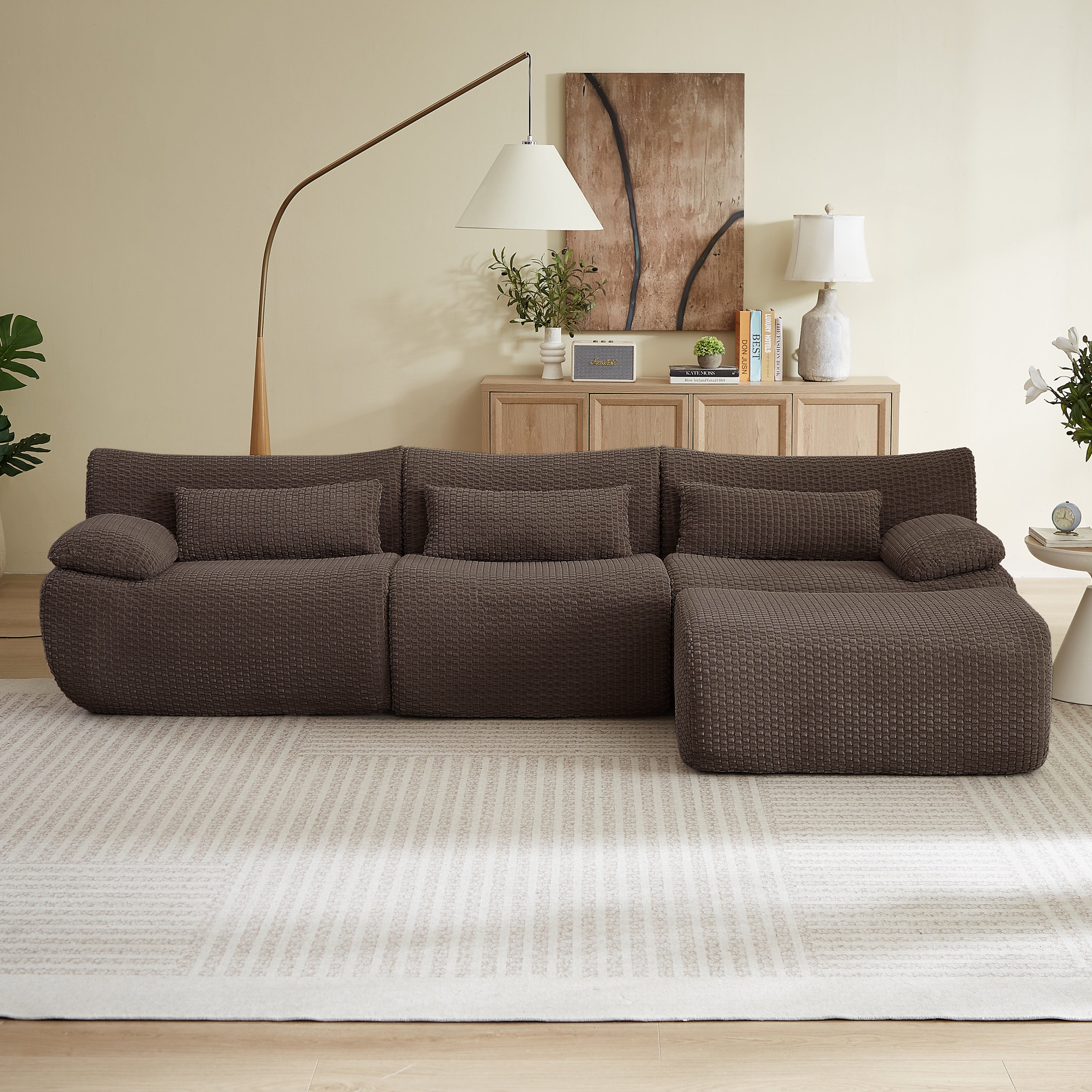 Modern L-shaped modular sectional sofa in dark brown textured fabric with oversized, boneless cushions on a neutral rug.