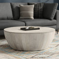 Elmbrook Drum Coffee Table in rustic white wood placed in a modern living room with a gray sofa and patterned rug. Ideal for coastal or contemporary decor.