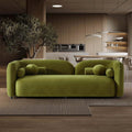 Olive green velvet Japandi sofa with a curved, low-profile silhouette and matching cylindrical bolster cushions.