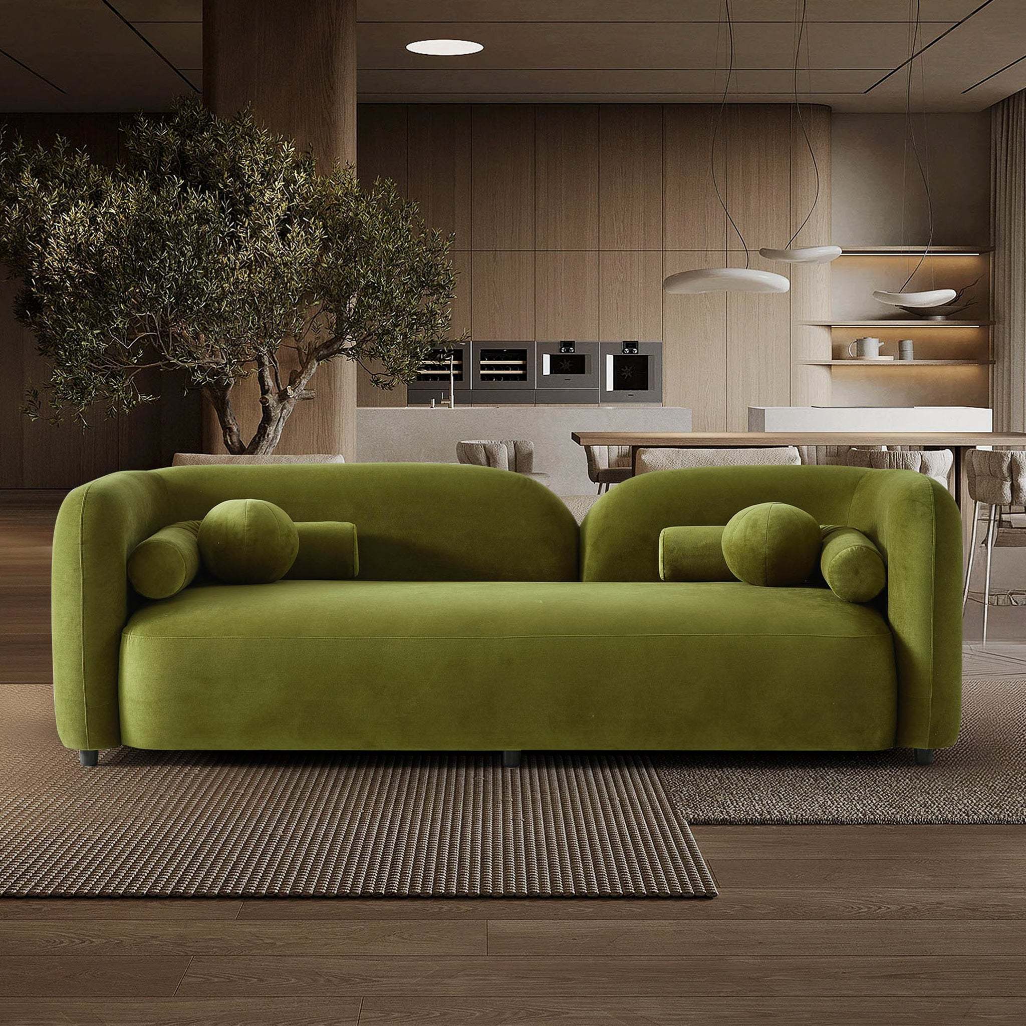 Olive green velvet Japandi sofa with a curved, low-profile silhouette and matching cylindrical bolster cushions.