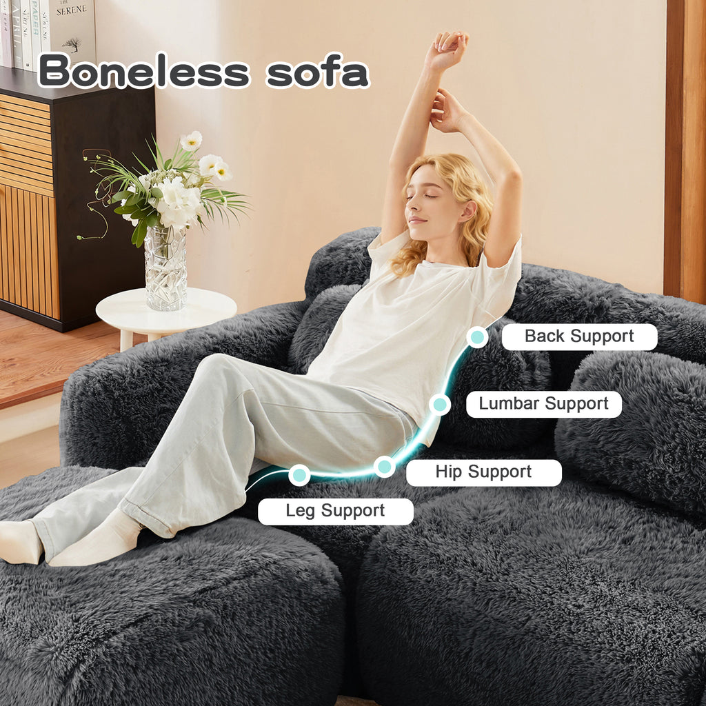 Woman relaxing on dark grey plush sectional sofa with labeled ergonomic support zones for back, lumbar, hip, and legs.