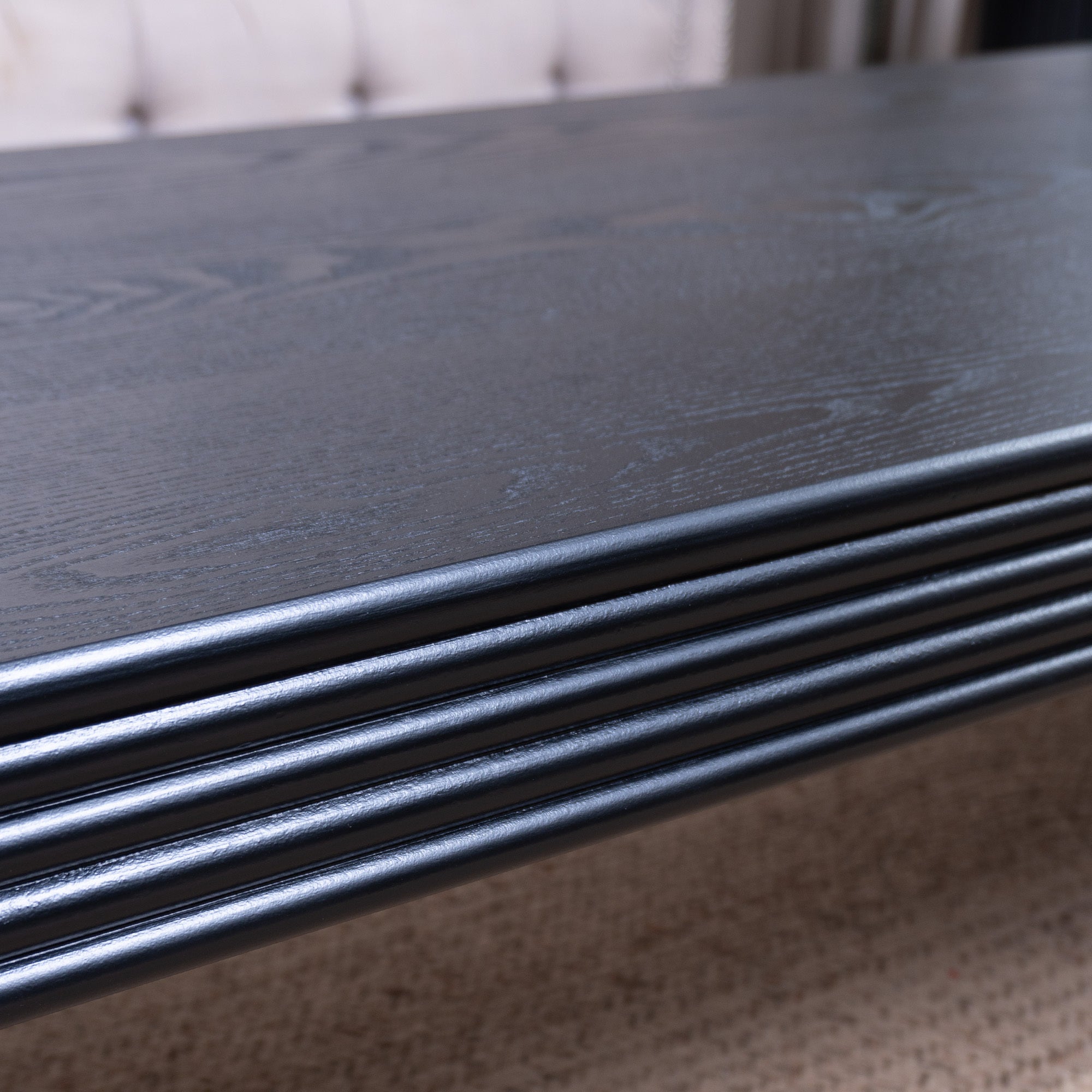 Zoomed-in view of the ribbed edge and wood grain surface of the black coffee table, highlighting its quality craftsmanship.