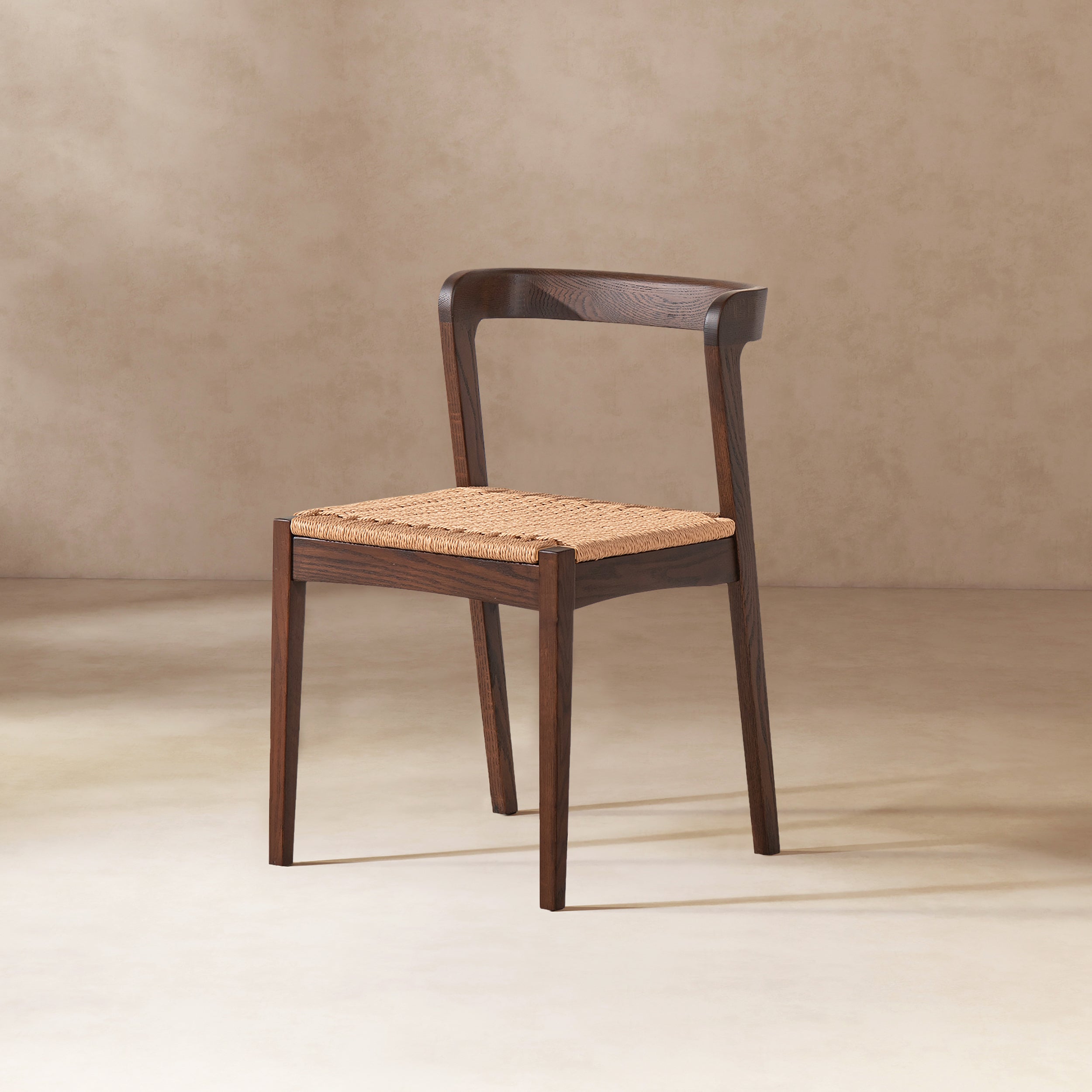 Single Capri Oak Wood Dining Chair in Dark Brown Red Oak on neutral background, emphasizing its minimalist silhouette and woven seat.