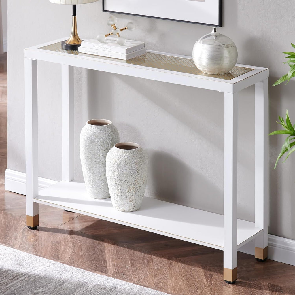 Modern 2-tier white console table with a glass top, gold accents, and a lower shelf, staged with home decor.