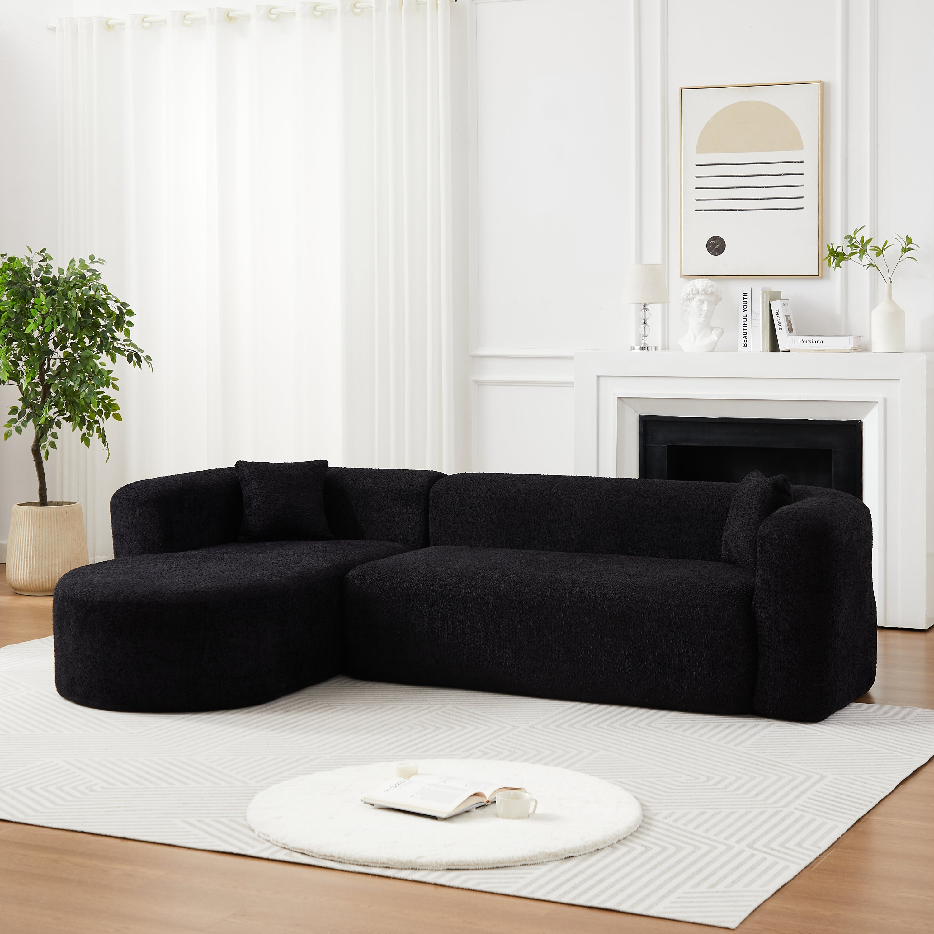 Black modular sectional sofa with soft chenille fabric and rounded chaise, arranged in a cozy corner of a contemporary living room.