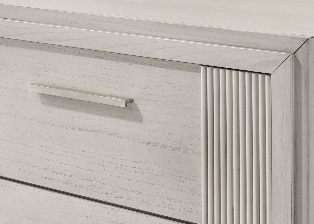 Close-up of contemporary white nightstand drawer with textured fluted detailing and sleek metal handle for a modern bedroom look.