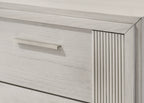 Close-up of contemporary white nightstand drawer with textured fluted detailing and sleek metal handle for a modern bedroom look.