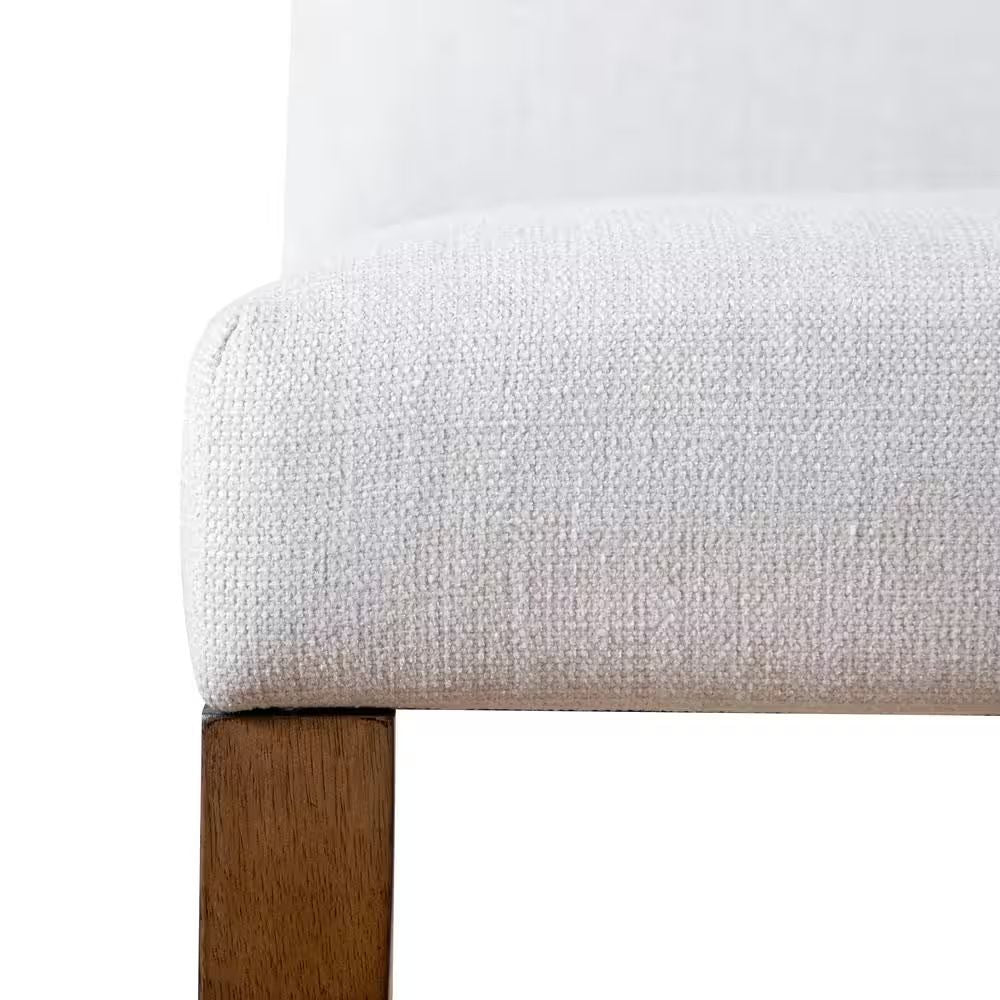 Detail view of the seat cushion and wooden leg on rustic upholstered dining chair, emphasizing craftsmanship and fabric quality.