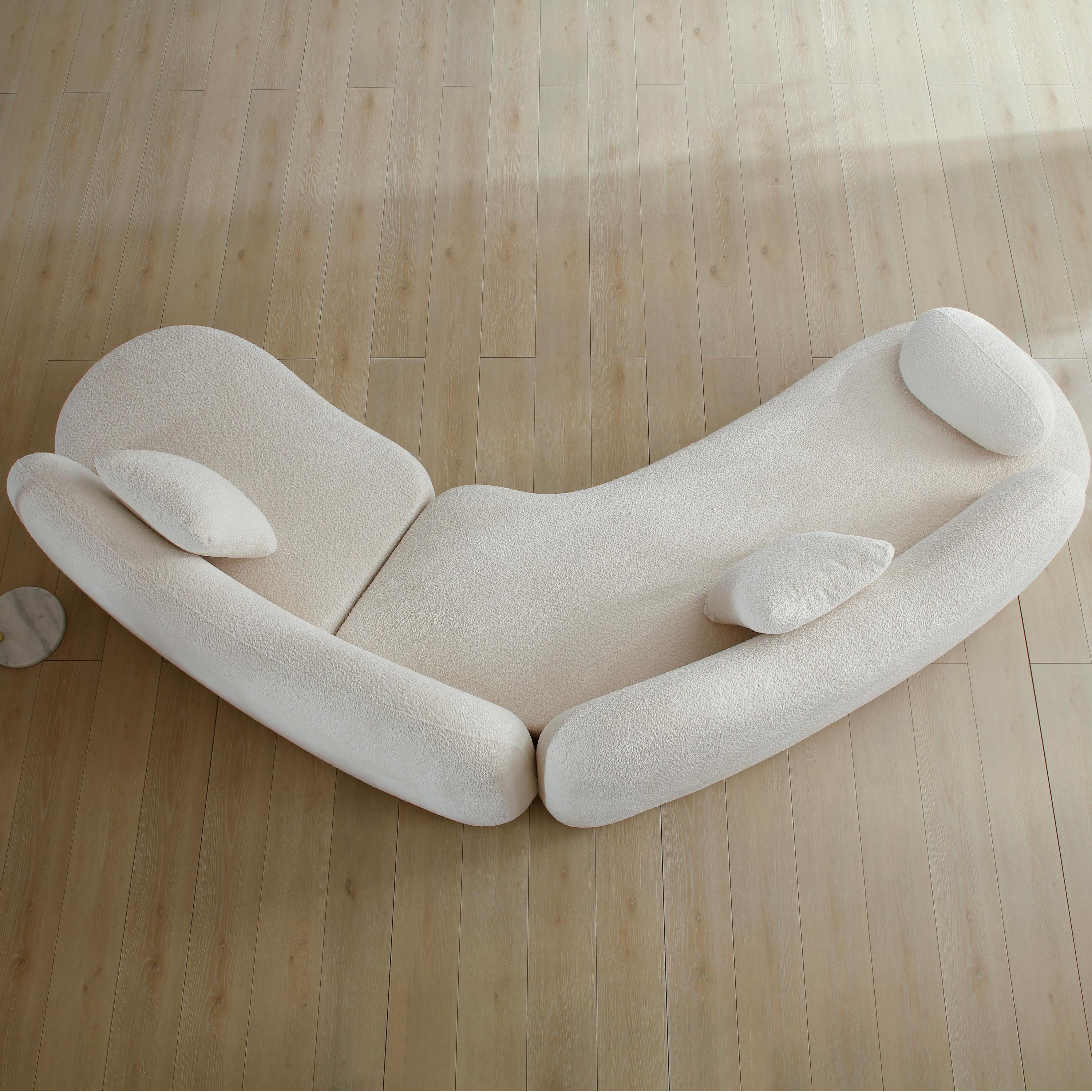 Overhead view of white boucle curved sectional sofa with 5-seater capacity and sculptural design, placed on light wood flooring.