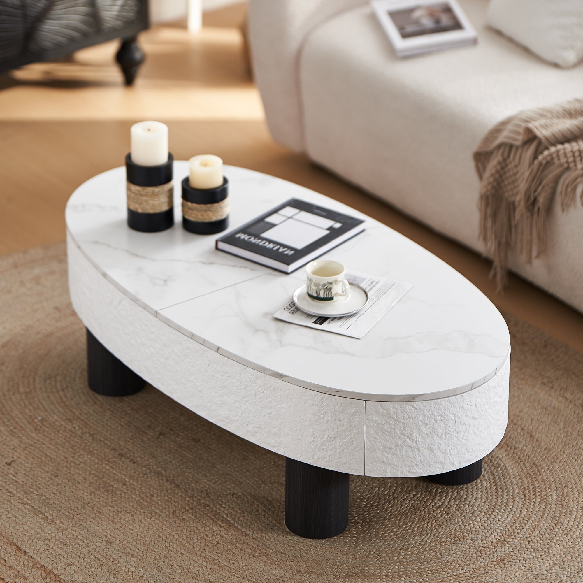 Modern oval coffee table with storage and faux marble top in a cozy living room. Features black legs and textured white sides.
