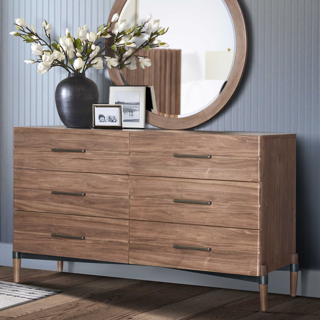 Modern walnut dresser with six drawers and round mirror in elegant room. Features antique bronze hardware and sleek design.