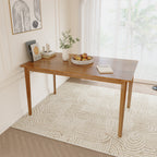 Solid wood dining table in a bright room with modern decor. Features a spacious surface and natural wood finish.